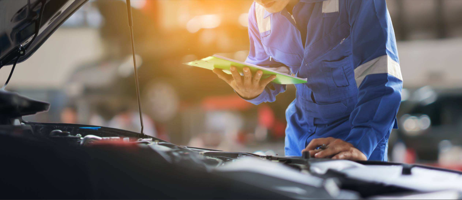 Automotive technician inspecting a vehicle engine during a service inspection.