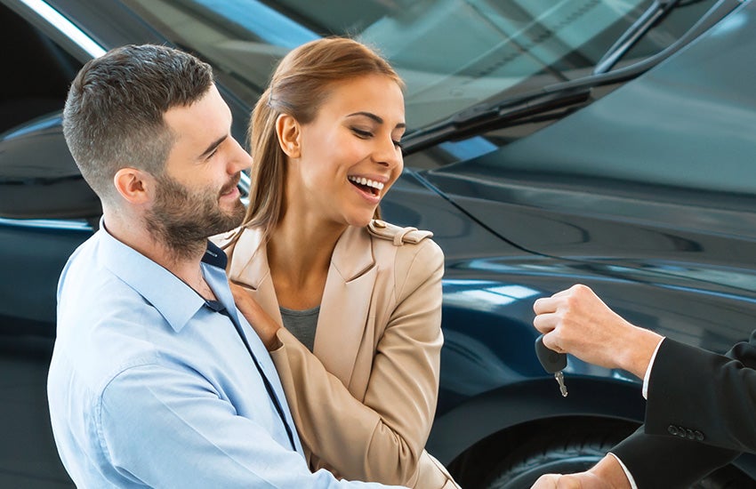 Happy couple receiving car keys at a dealership